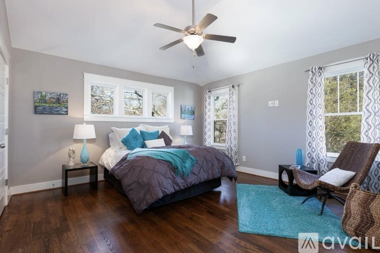 A bedroom with a bed, chair, and a ceiling fan.