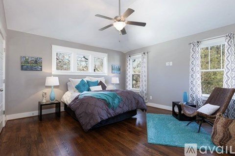 A bedroom with a bed, chair, and a ceiling fan.