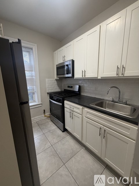 A kitchen with white cabinets and a black fridge.