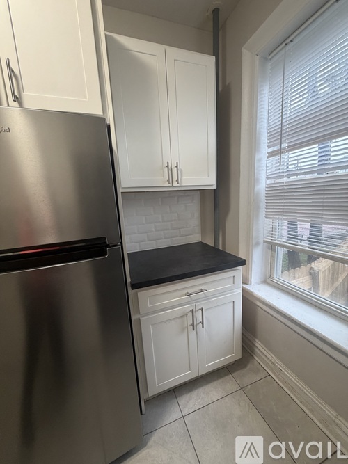 A kitchen with a stainless steel refrigerator and white cabinets.