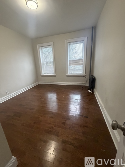 A room with wooden floors and two windows.