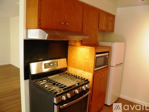 A kitchen with a black stove top oven and wooden cabinets.
