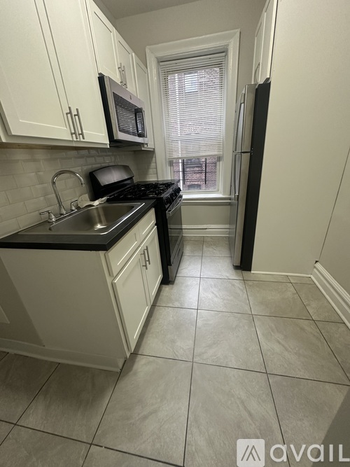 A kitchen with white cabinets and black countertops.