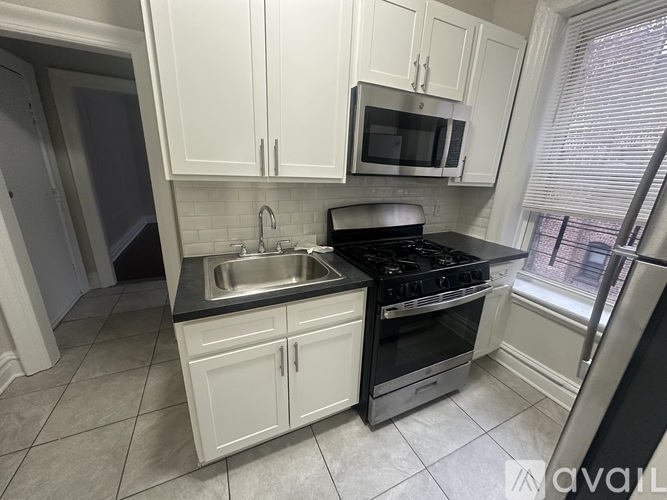 A kitchen with white cabinets and black appliances.