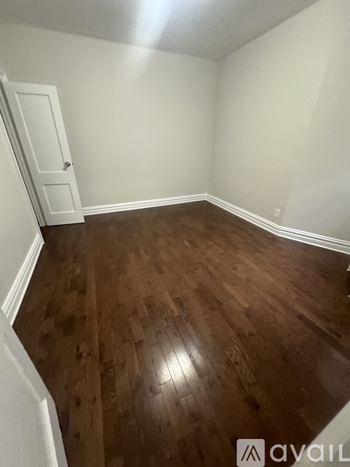A room with wooden flooring and a white door.