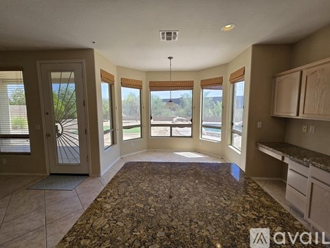 A spacious living room with a rug on the floor and a view of the backyard through the windows.