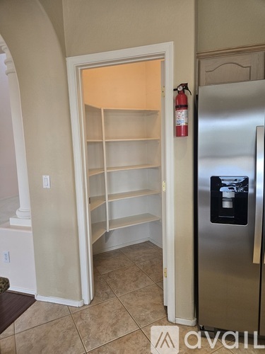 A kitchen with a refrigerator and an open door to a pantry.