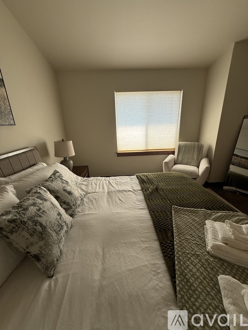 A bedroom with a large bed and a window with blinds.