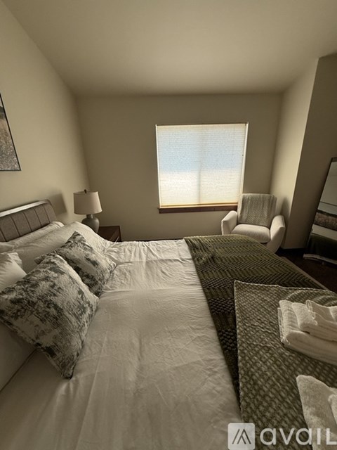 A bedroom with a large bed and a window with blinds.