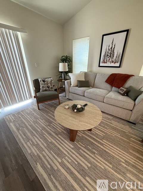 A living room with a grey couch, a wooden coffee table, and a painting on the wall.