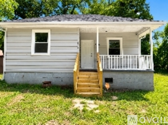 A small house with a grey siding and a white door.