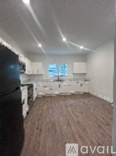 A kitchen with a black fridge and wooden floors.
