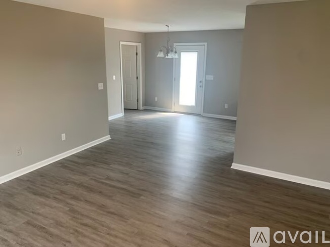 A spacious room with wooden flooring and a chandelier hanging from the ceiling.