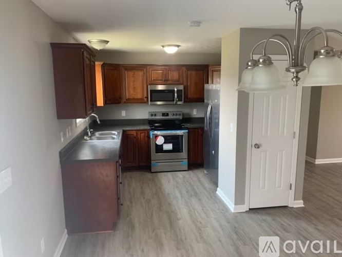 A kitchen with dark wood cabinets and a stainless steel refrigerator.