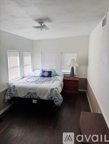 A bedroom with a bed, nightstand, and a window.