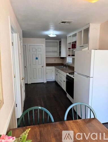 A kitchen with white appliances and a wooden table.