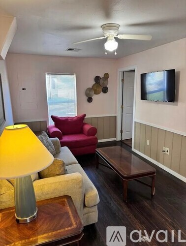 A living room with a yellow lamp and a red chair.