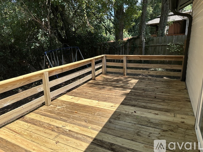 A wooden deck with a railing and trees in the background.