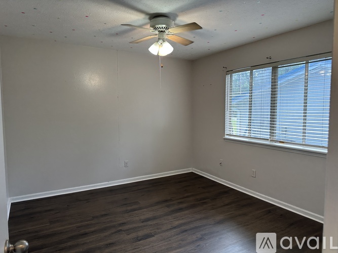 A room with a ceiling fan and wooden flooring.
