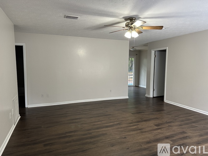 A spacious room with a ceiling fan and hardwood flooring.