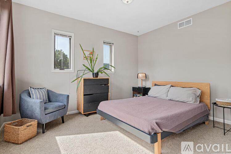 A bedroom with a bed, chair, and plant.