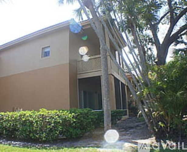 A house with a brown and beige exterior is surrounded by greenery.