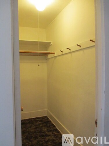 A small, empty room with a carpeted floor and a doorway leading to another room.