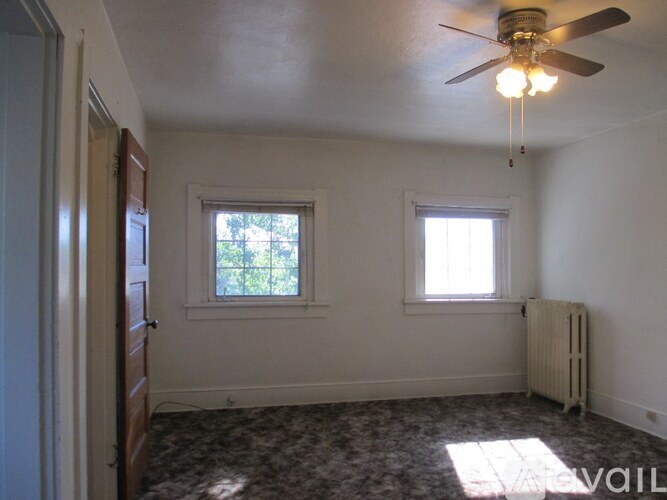 A room with a ceiling fan and two windows.