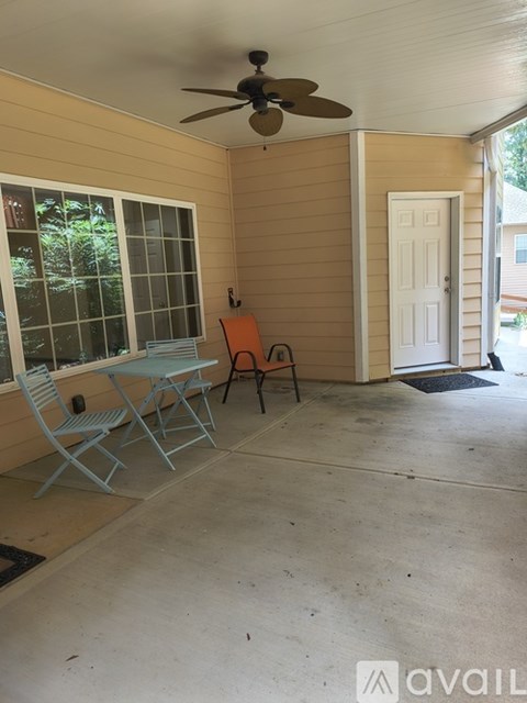 A patio with a table and chairs and a ceiling fan.