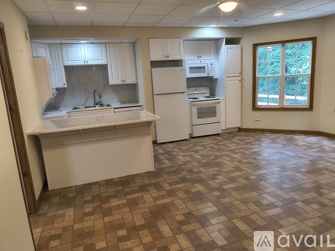 A kitchen with brown tiled floors and white appliances.