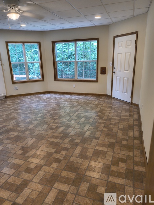 A room with brown tiled flooring and two windows.