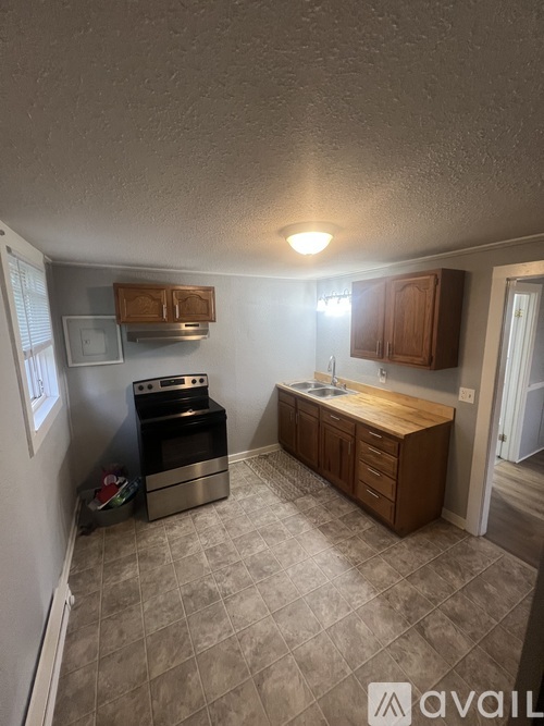 A kitchen with a stove, sink, and cabinets.