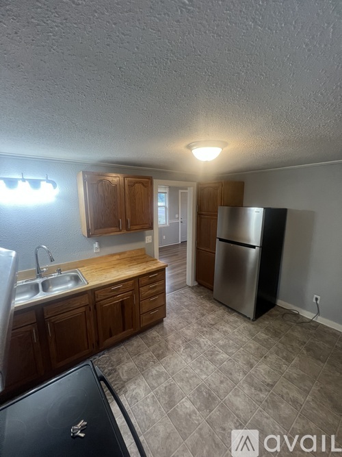 A kitchen with wooden cabinets and a black fridge.