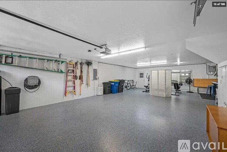 A spacious garage with a grey floor and white walls, equipped with various tools and storage solutions.
