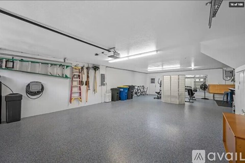 A spacious garage with a grey floor and white walls, equipped with various tools and storage solutions.