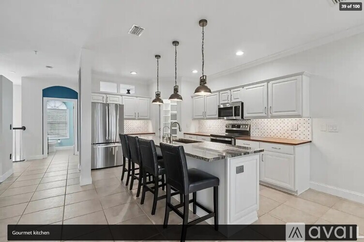 A gourmet kitchen with white cabinets and black chairs.