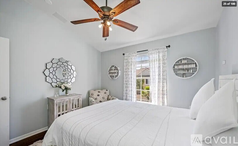 A white bedroom with a large bed and a ceiling fan.
