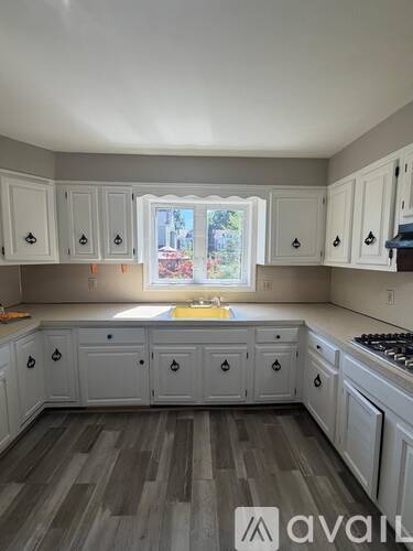 A kitchen with white cabinets and a window.
