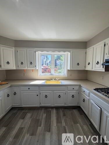 A kitchen with white cabinets and a window.