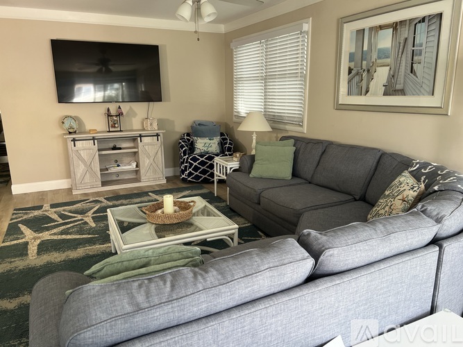 A living room with a grey couch, a coffee table, and a television.