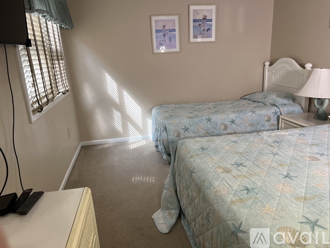 A bedroom with two beds and a window with blinds.