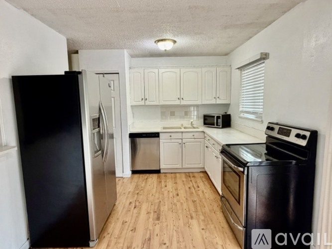 A kitchen with black appliances and white cabinets.