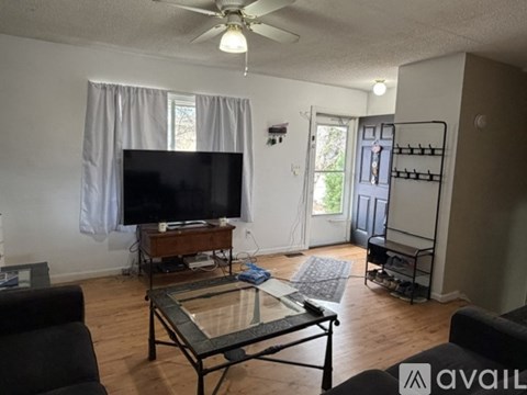 A living room with a glass coffee table and a flat screen TV.