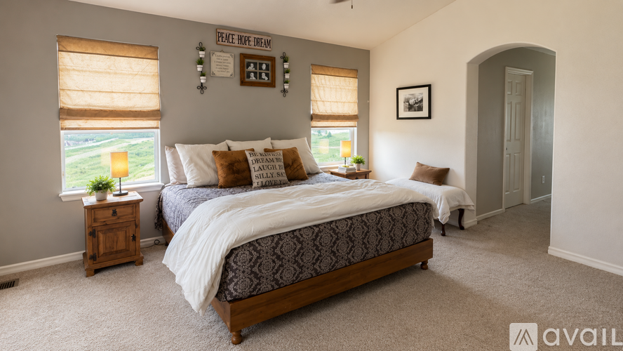 A bedroom with a large bed and a window with blinds.