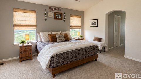 A bedroom with a large bed and a window with blinds.