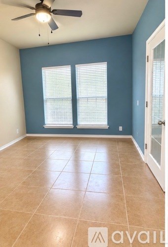 A room with a ceiling fan and tile flooring.