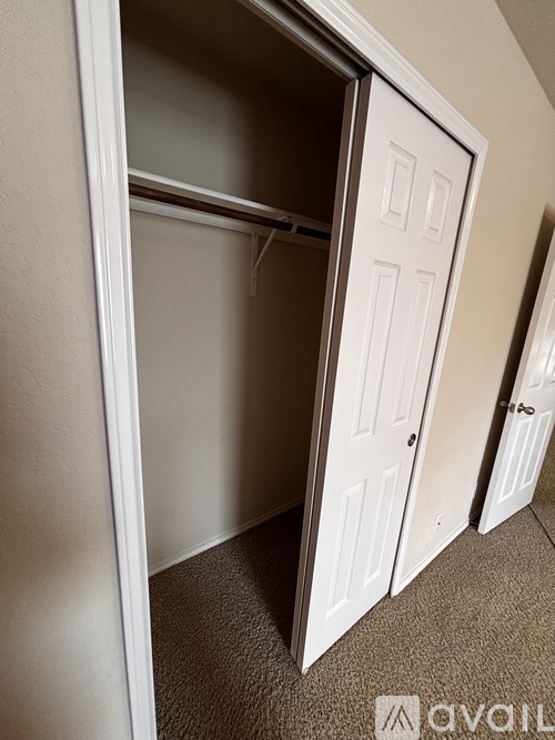 A white door is open to a carpeted hallway.