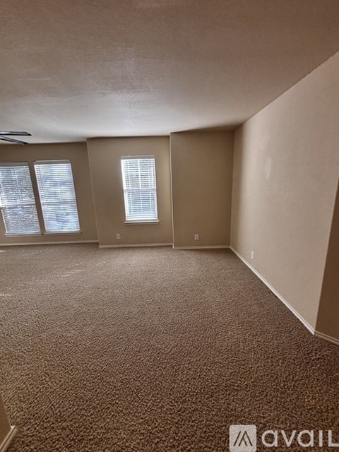 A room with carpeted floor and a window with blinds.