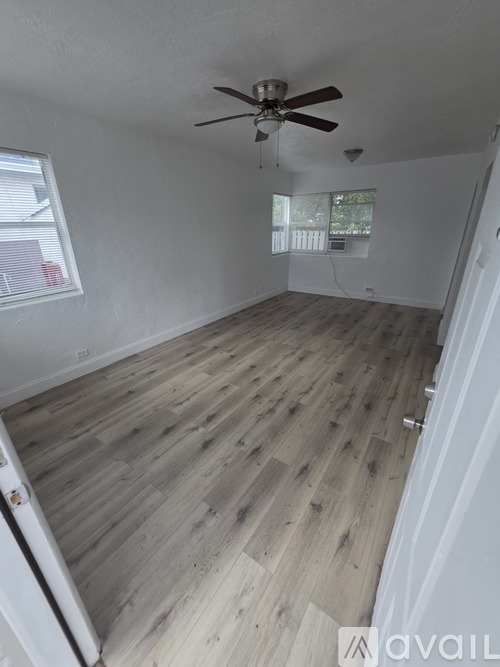 A room with a ceiling fan and wooden flooring.