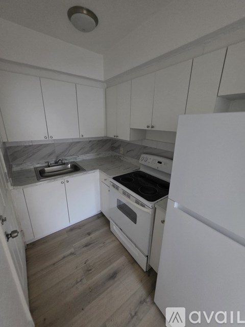 A kitchen with white cabinets and a white fridge.